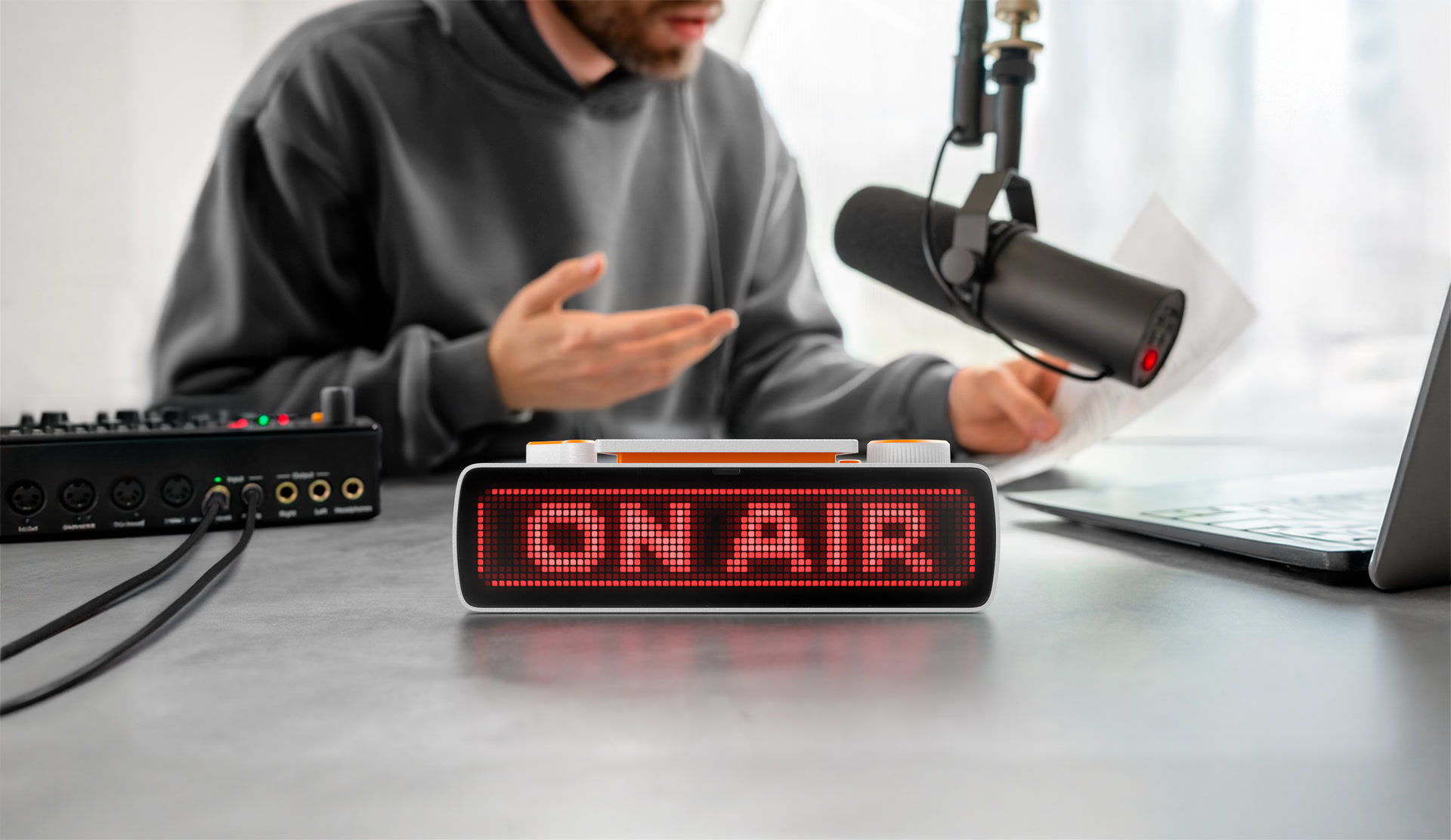 BUSY Bar showing an ON AIR status on a podcast desk beside a microphone